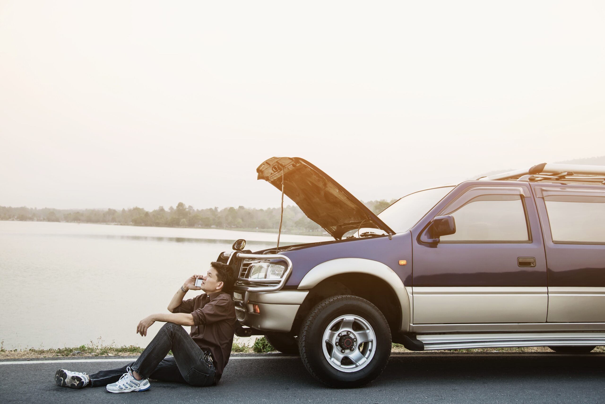 man try fix car engine problem local road